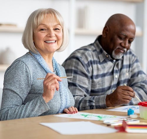 positive-senior-woman-enjoying-painting-with-brush